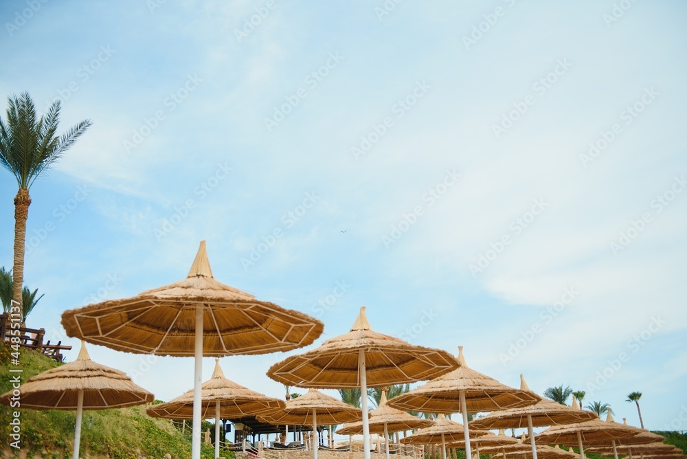 Umbrella and deck chair around outdoor swimming pool in hotel resort with sea ocean beach and coconut palm tree Umbrella and deck chair around outdoor swimming pool in hotel resort with sea ocean beach and coconut palm tree