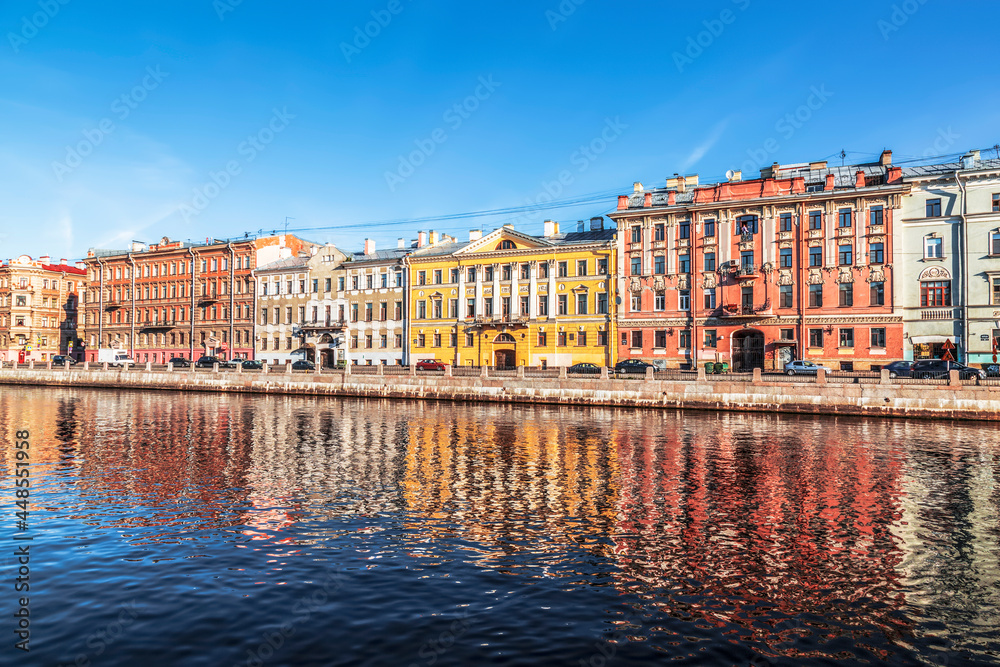 Ancient tenement houses on the Fontanka River embankment in the early morning and their reflection in the river. Saint Petersburg, Russia