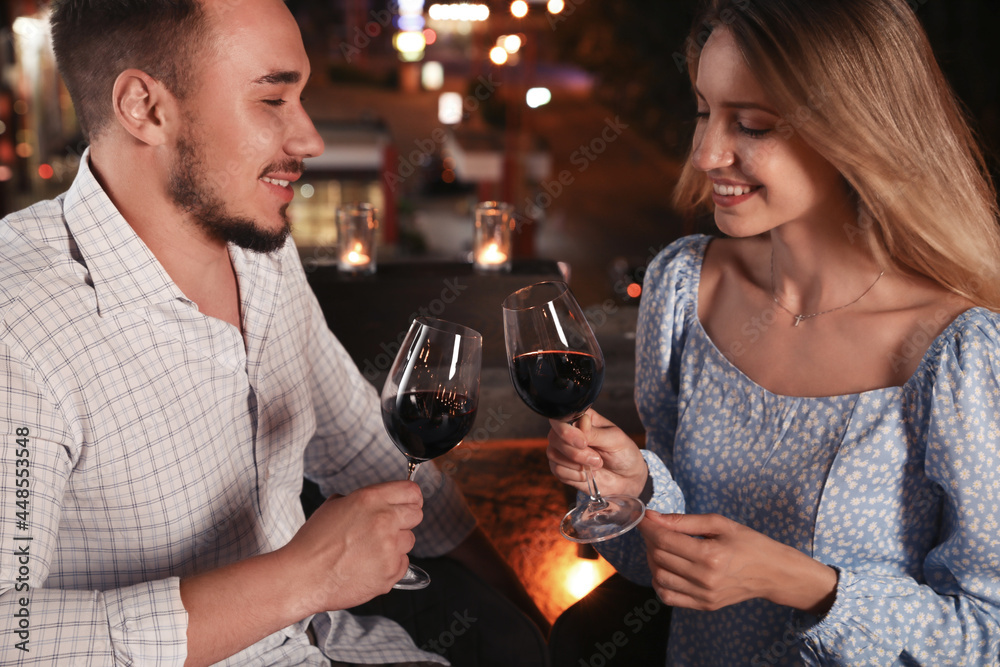 Romantic couple with glasses of red wine on cafe terrace at night Romantic couple with glasses of red wine on cafe terrace at night