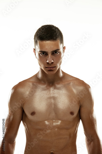 Portrait of young muscular man, male athlete, runner isolated on white studio background. Concept of sport, healthy lifestyle. Power and beauty