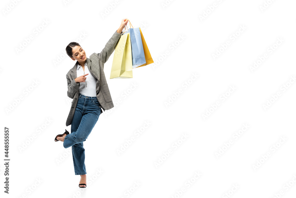 Smiling woman pointing with finger at shopping bag on white background Smiling woman pointing with finger at shopping bag on white background