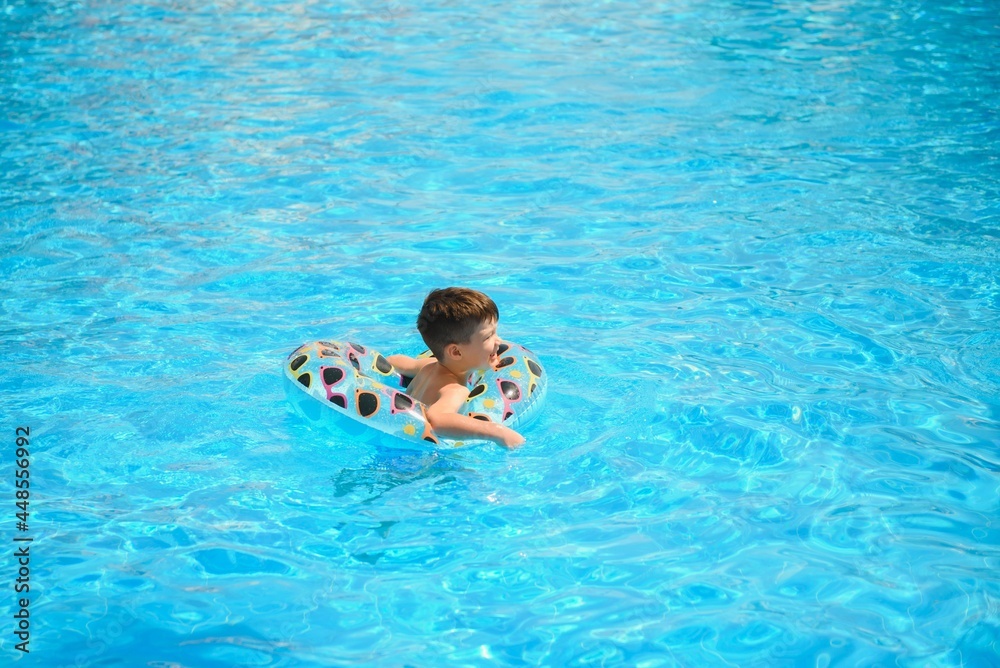 Kids summer vacation. Child swimming in pool. Kids having fun at aquapark. Funny boy on inflatable rubber circle. Summertime. Attractions concept