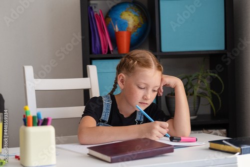  cute caucasian redhead girl studying at home photo