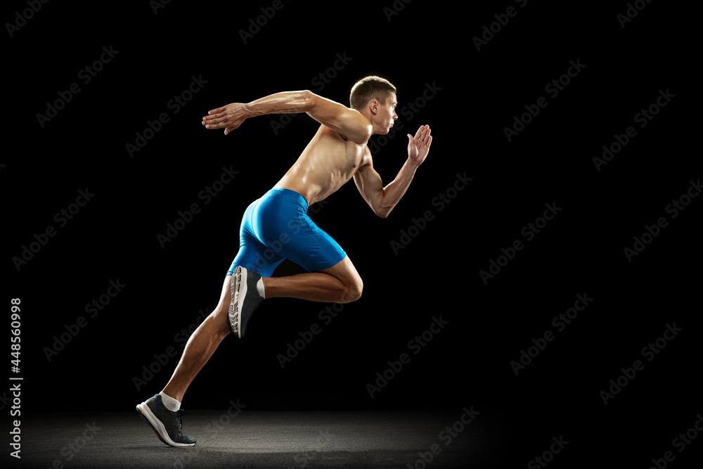 One Caucasian professional male athlete, runner training isolated on dark studio background. Muscular, sportive man. Concept of sport, healthy lifestyle