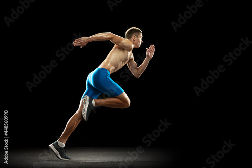 One Caucasian professional male athlete, runner training isolated on dark studio background. Muscular, sportive man. Concept of sport, healthy lifestyle