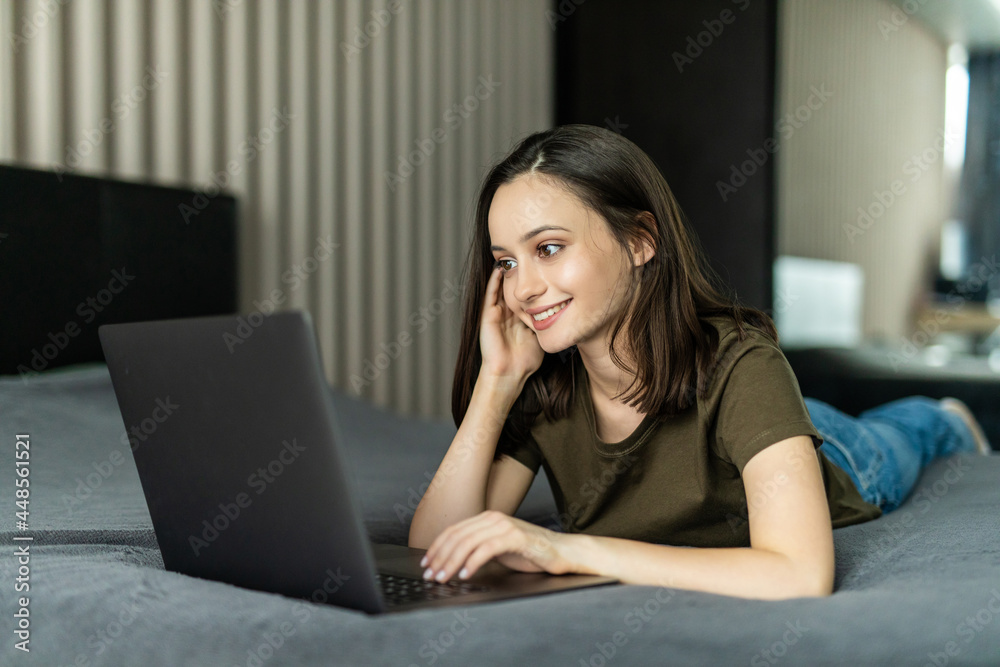 Beautiful young woman lying on bed and using computer laptop for using social media and shopping online relax in cozy bedroom in holiday Beautiful young woman lying on bed and using computer laptop for using social media and shopping online relax in cozy bedroom in holiday