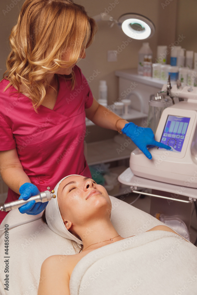 Young woman getting microcurrents skin cleansing and face treatment at beauty salon