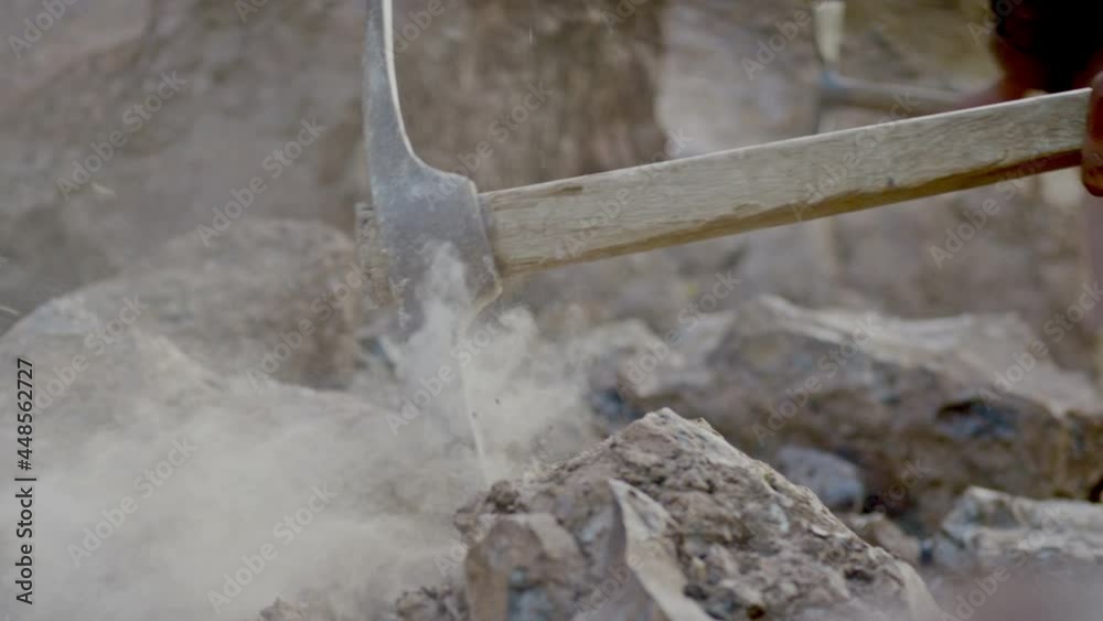 Miner or gold digger breaking rock by digging axe . Close up of pickaxe hitting rocks .  Shot on RED EPIC DRAGON Cinema Camera in slow motion.