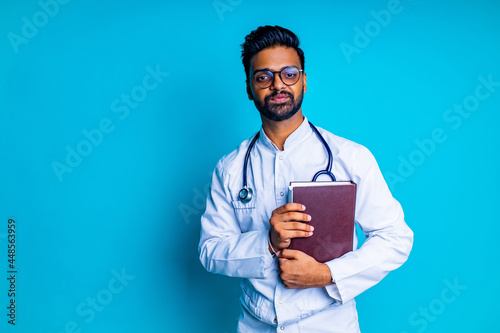 young latin hispanic medican man wear eye glasses with stethoscope in blue studio wall background photo