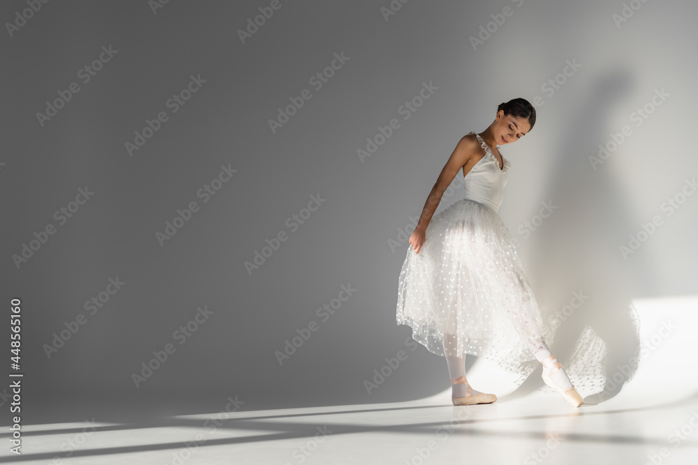Naklejka premium Ballerina looking at pointe shoe on grey background