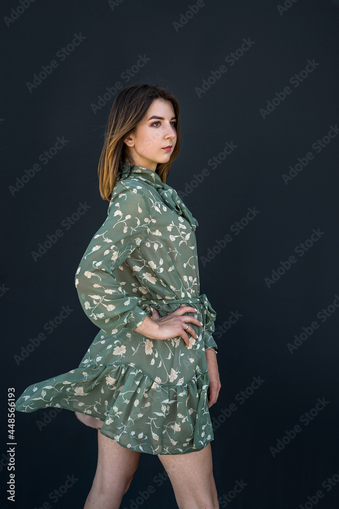 Calm beautiful young woman in elegant green dress near black wall Calm beautiful young woman in elegant green dress near black wall