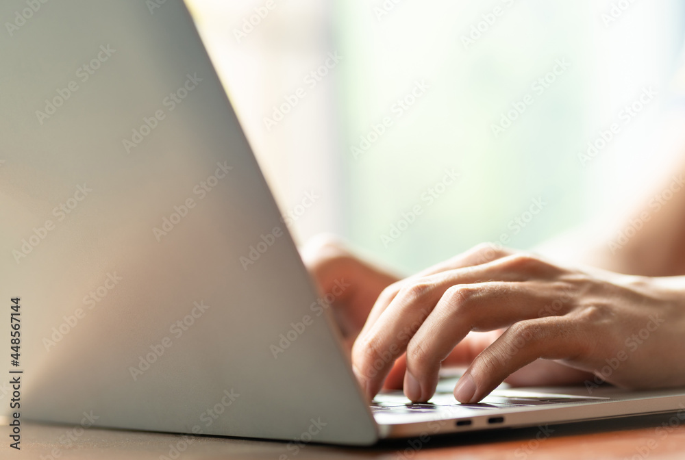man is using a laptop to search for business information, stocks on desk and communicate using social media with colleagues using the Internet. Closeup hands typing keyboard and free copy space