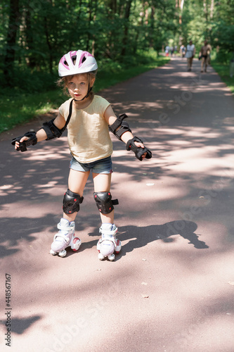 Kid in protective sportswear. little girl is rollerblading in the park.