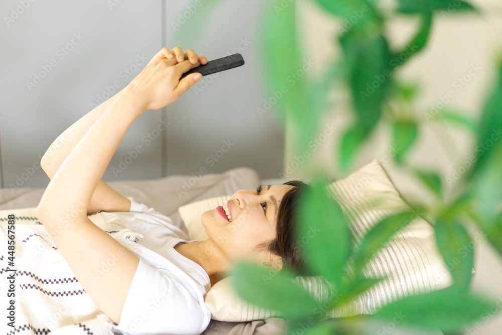 ベッドでスマホを使う若い女性