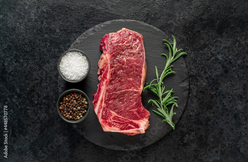 Raw marbled beef New York steak with spices on a stone background