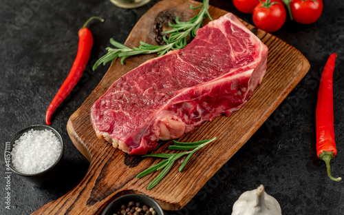 Raw marbled beef New York steak with spices on a stone background