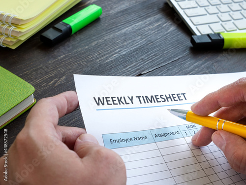 Man filing in weekly timesheet for employee in the office. photo