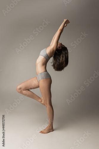 Sports, yoga and healthy lifestyle. Young beautiful sportive woman in lingerie posing isolated over gray studio background. Natural beauty concept.