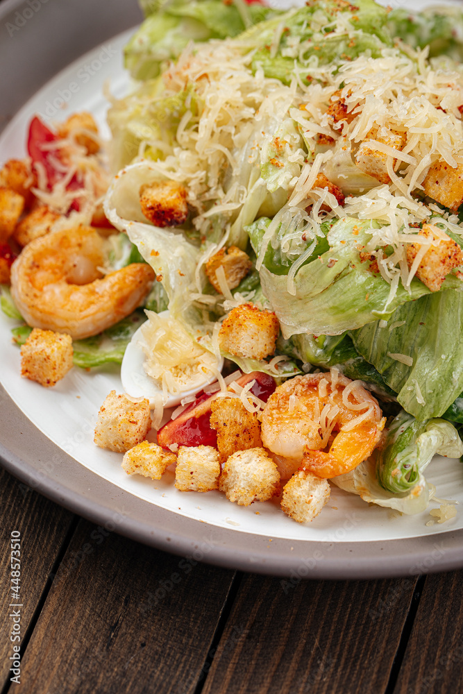 Caesar salad with shrimp and croutons on wooden background Caesar salad with shrimp and croutons on wooden background