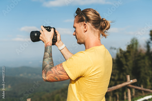 Man photographer in yellow tshirt making photo of beautiful landscape