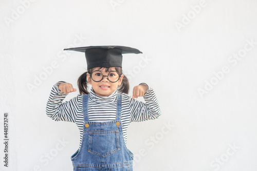 children girl wearing a graduate cap over white background very happy and excited doing winner gesture with arms raised, smiling and screaming for success. Celebration concept.