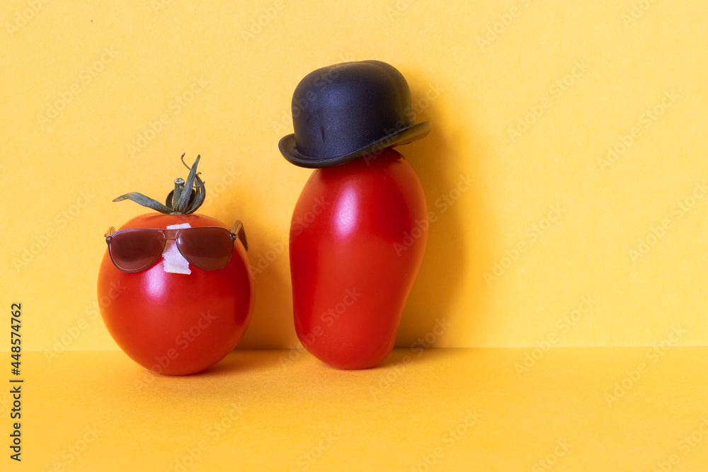 Ripe red tomato character in a black hat and small red tomato