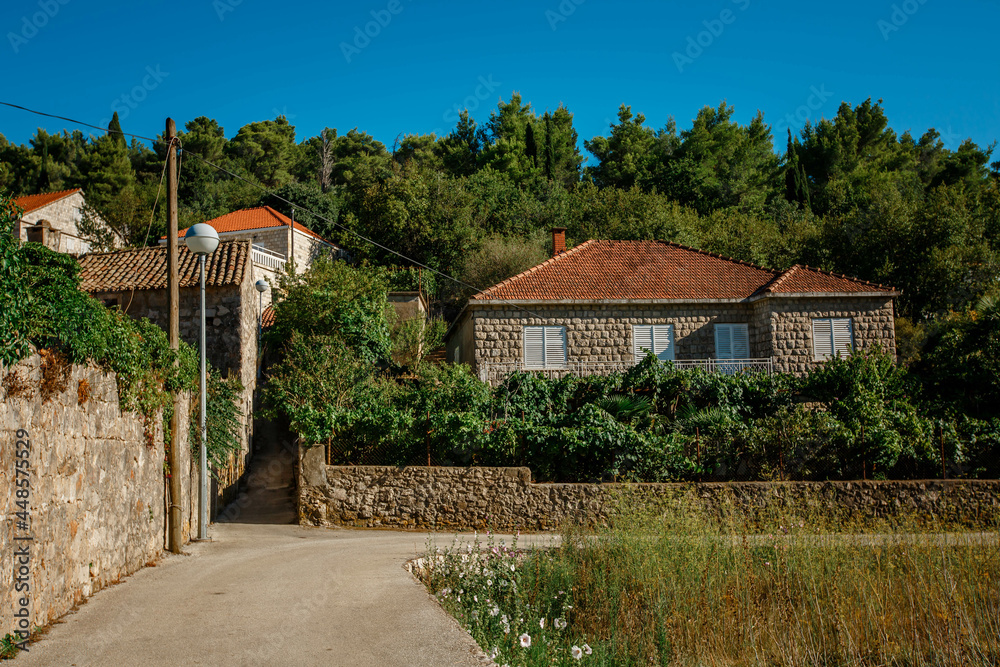 Mediterrean old house with orange roof in the foreground and high rocky mountains in the back