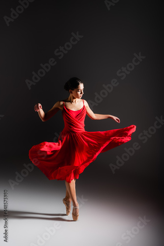 Ballerina in dress spinning on black background