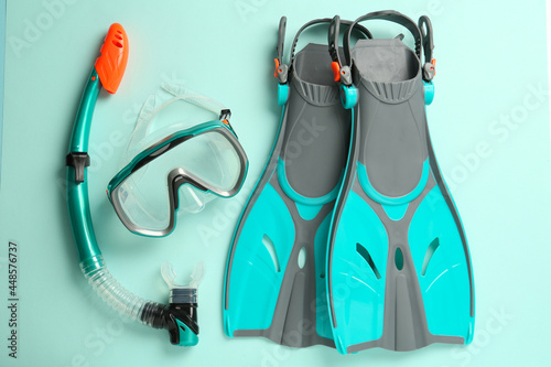 Pair of flippers, snorkel and diving mask on turquoise background, flat lay