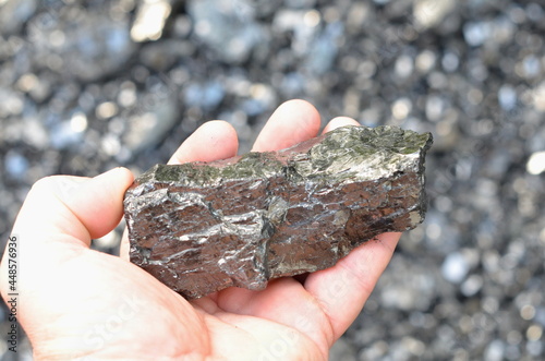 A piece of coarse anthracite coal lies in a man's hand.