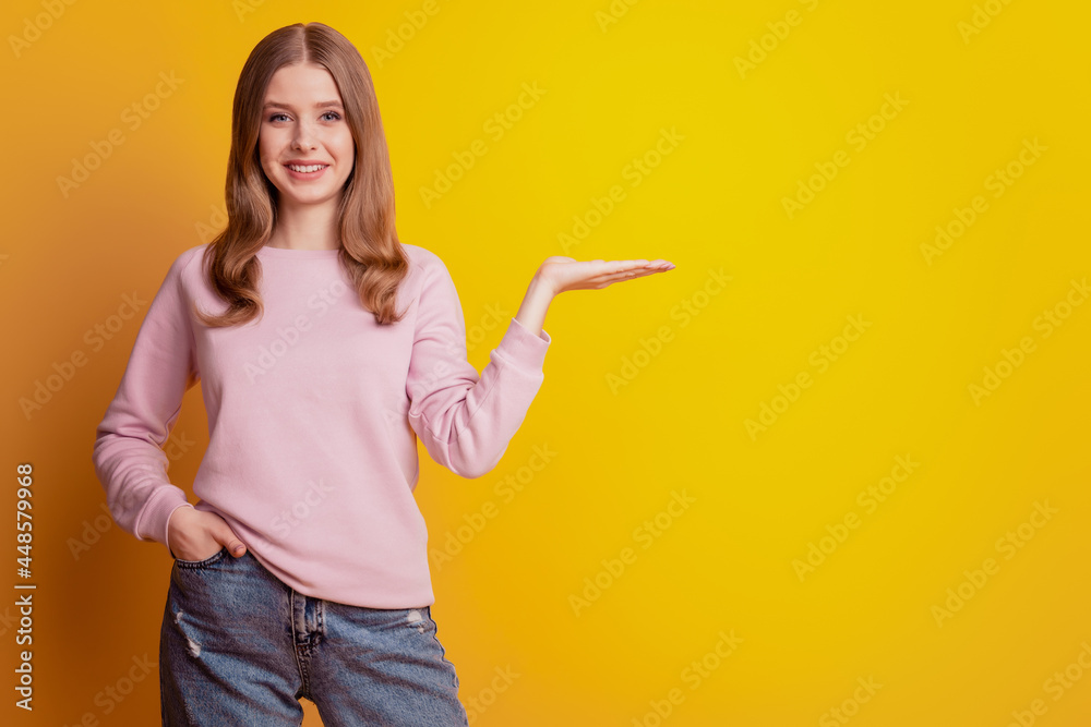 Photo of charming girl hand hold empty space on yellow background Photo of charming girl hand hold empty space on yellow background