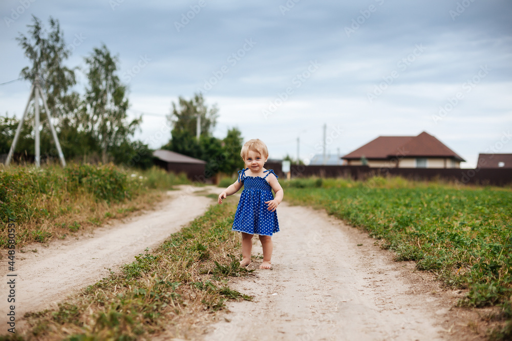 Little girl of two years old on country road.