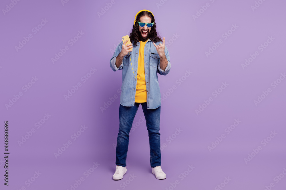Closeup of cheerful guy hold smartphone have fun show horns gesture