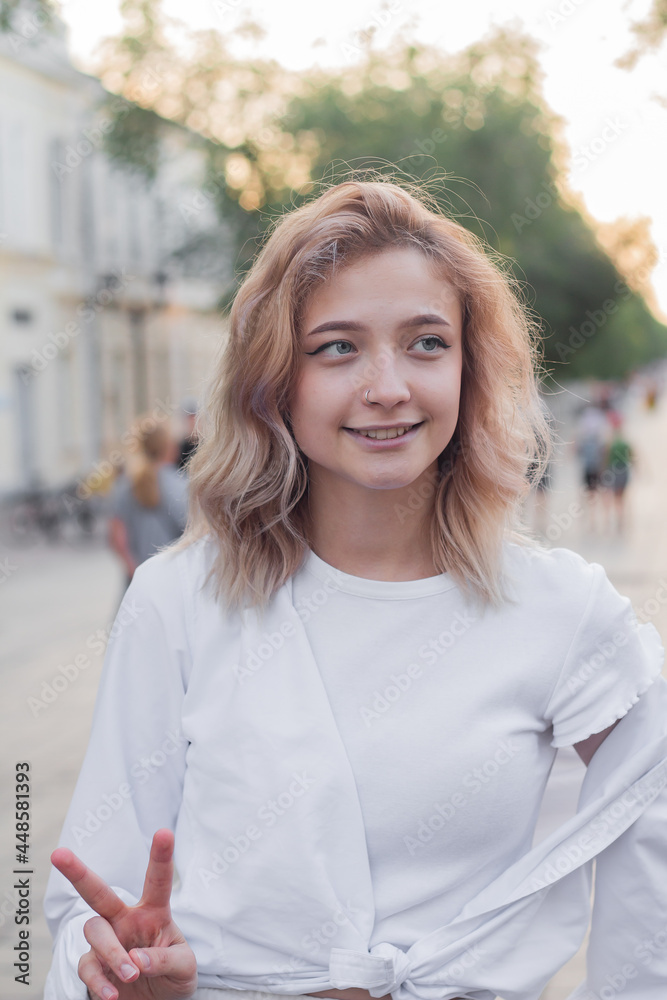 Portrait of a beautiful young woman in white clothes on the alley of the city