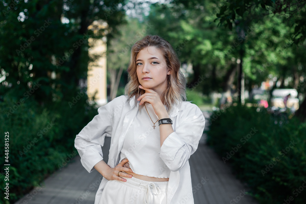 Portrait of a beautiful young woman in white clothes on the alley of the city Portrait of a beautiful young woman in white clothes on the alley of the city