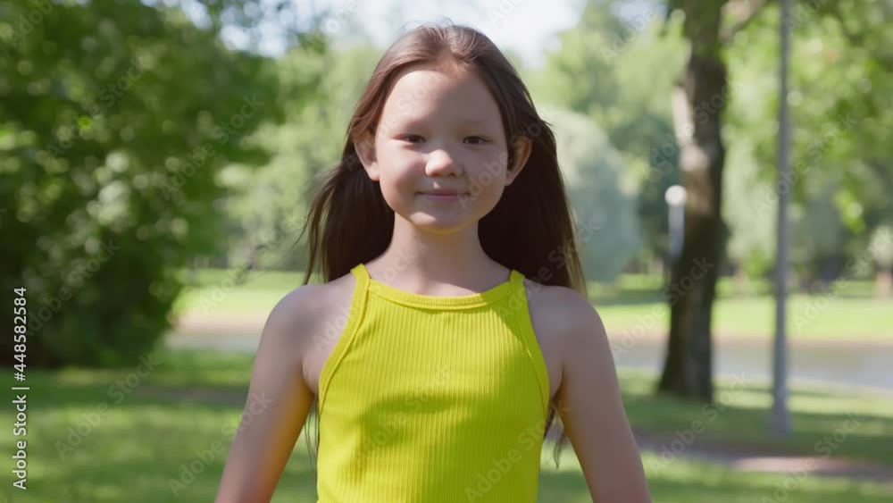 Vidéo Stock Dolly push shot of cute asian preteen girl looking at camera outside | Adobe Stock