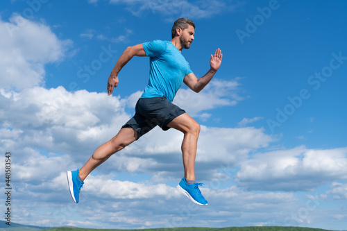 healthy sportsman with muscular body running in sportswear outdoor on sky background, sport