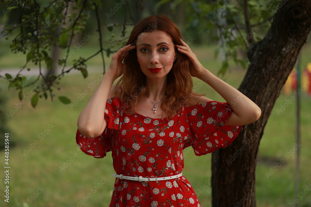 Woman in red dress near a tree in the park Woman in red dress near a tree in the park