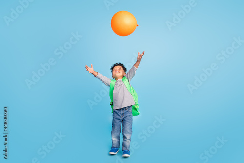 Full length body size view of nice cheerful boy throwing air ball celebrating isolated over bright blue color background © deagreez