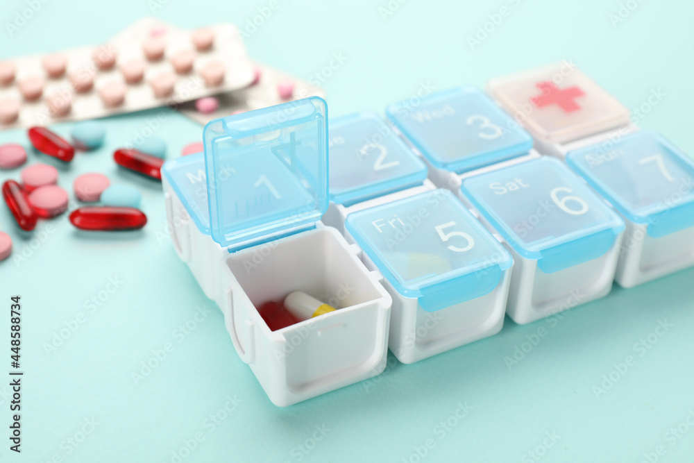Plastic box with different pills on turquoise background, closeup Plastic box with different pills on turquoise background, closeup