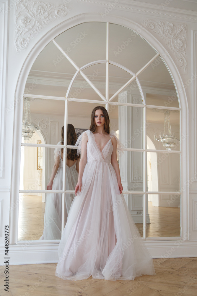 Portrait of a young girl of the bride in a gentle flowing dress in a chic interior.