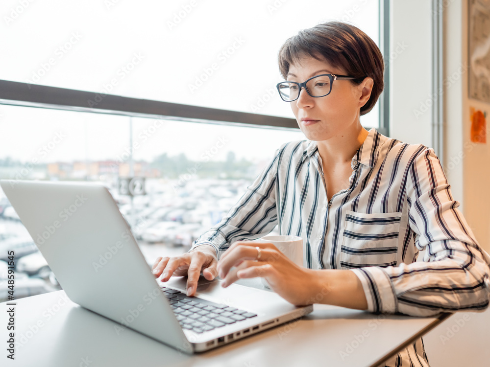 Business woman works with laptop in co-working center. Workplace for freelancers in business center. Business woman works with laptop in co-working center. Workplace for freelancers in business center.