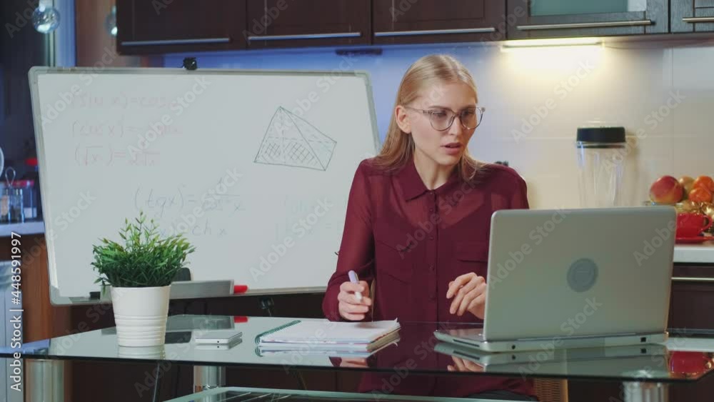 Medium shot of Business woman providing video conference by computer and showing information on whiteboard. Remote work concept.