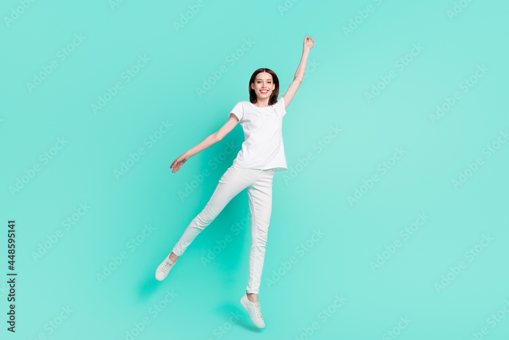 Full length photo of nice brunette hair millennial lady jump wear white t-shirt jeans isolated on teal color background Full length photo of nice brunette hair millennial lady jump wear white t-shirt jeans isolated on teal color background