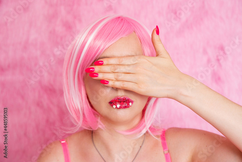 Portrait of a girl. Young woman in a pink wig closes her eyes with her hand on a pink background. Beauty  beauty  care  fashion close-up