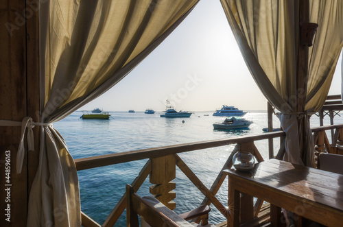 beach umbrellas and palm trees on the background of the red sea and ships in egypt © Sofiia