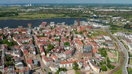 Fly above historic town centre next to sea bay. aerial panoramic view of streets lined by buildings with red tiled roofs photo