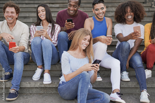 Group of young diverse friends using mobile phone in the city - Multiracial people having social moment and enjoy technology