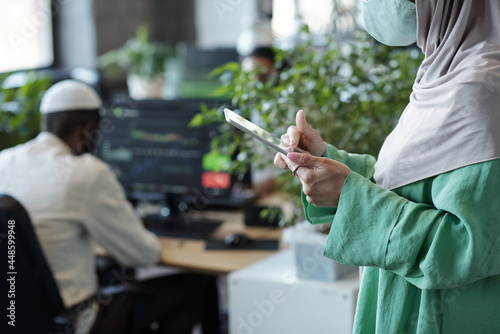 Hands of Muslim businesswoman using digital tablet in working environment