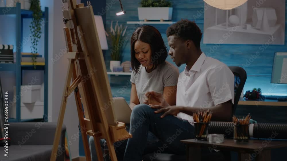 Couple of african american artists creating art drawing design sitting in workshop room at home. Black young people with creativity working on canvas and easel for modern masterpiece Couple of african american artists creating art drawing design sitting in workshop room at home. Black young people with creativity working on canvas and easel for modern masterpiece